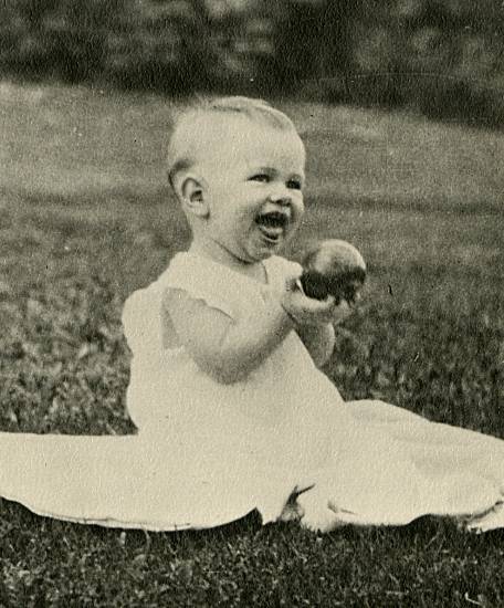 photograph of J. W. Fiegenbaum at age 6 months sitting on a blanket in the grass and obviously happy to be holding an apple