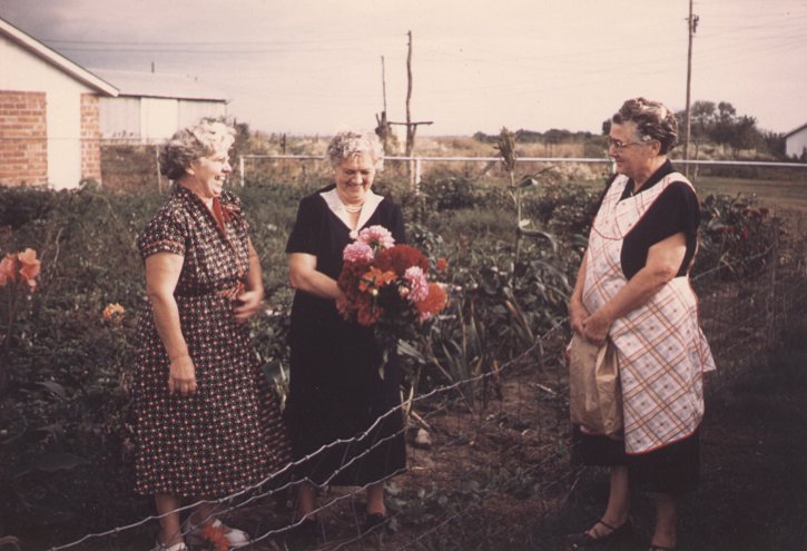 photo of Katherine M. (Maun) Fiegenbaum and her two sisters, Anna L. (Maun) Scott, Clara Maria (Maun) Ahman, outside in Katie's garden, laughing at a good story