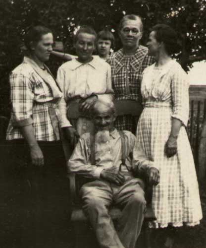 posing outside is Heinrich Friederich L. Starkebaum, seated in a rocking chair, with four of his grown daughters
